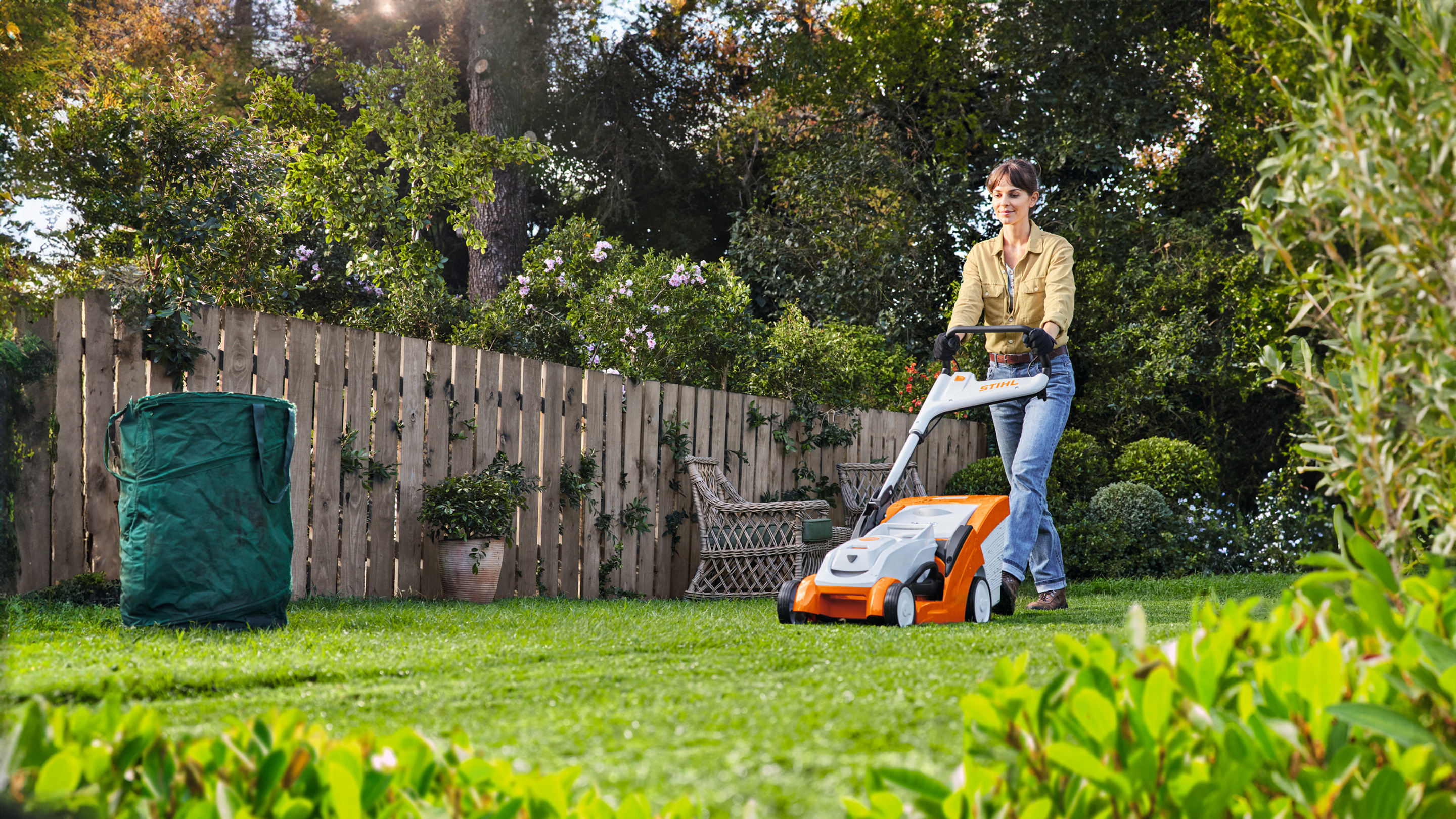 Une femme tond la pelouse avec une tondeuse à gazon à batterie STIHL RMA 239 C