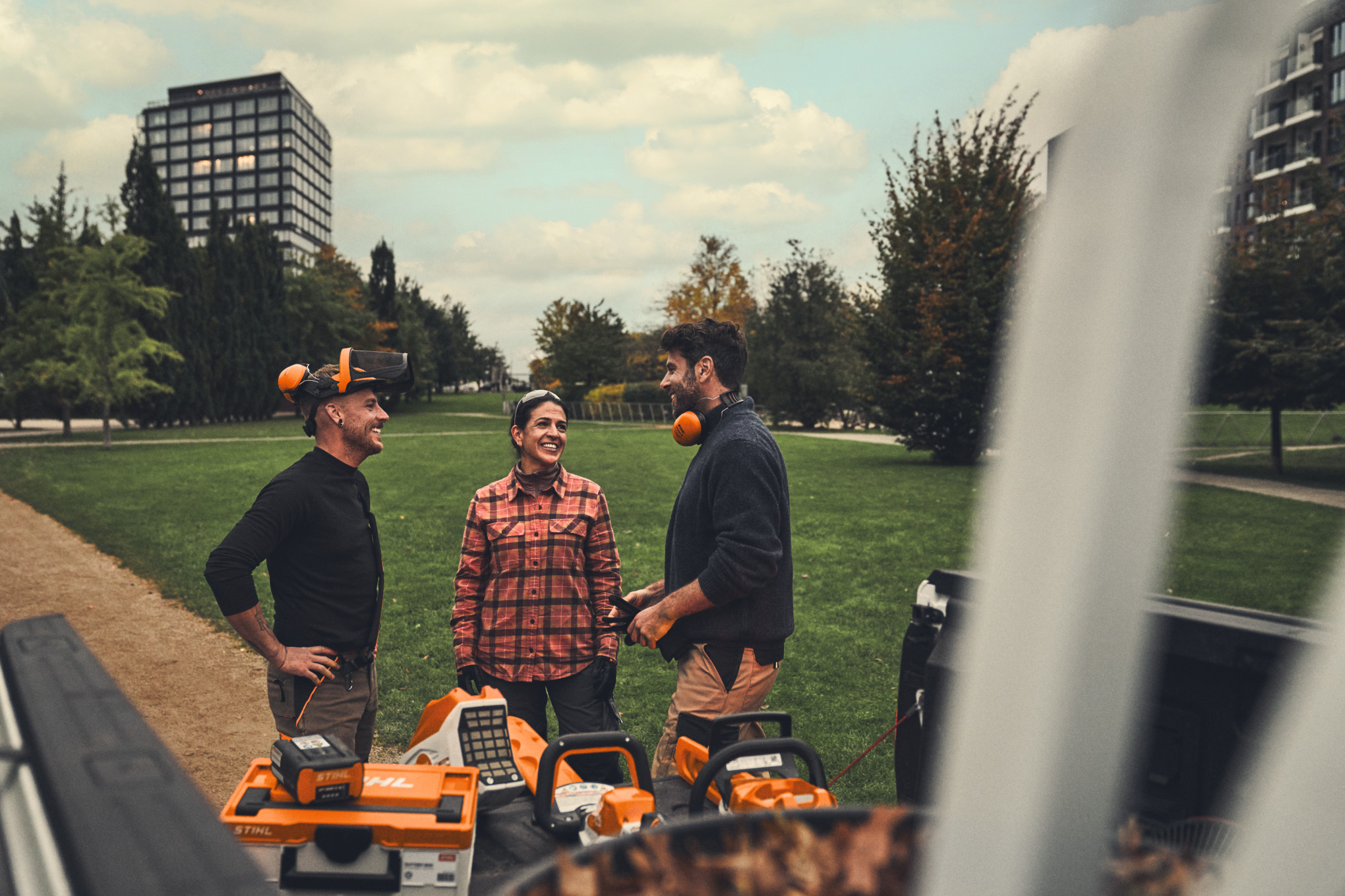 Una squadra di giardinieri e paesaggisti si trova davanti a un camion a pianale su cui sono appoggiati gli attrezzi professionali a batteria STIHL.