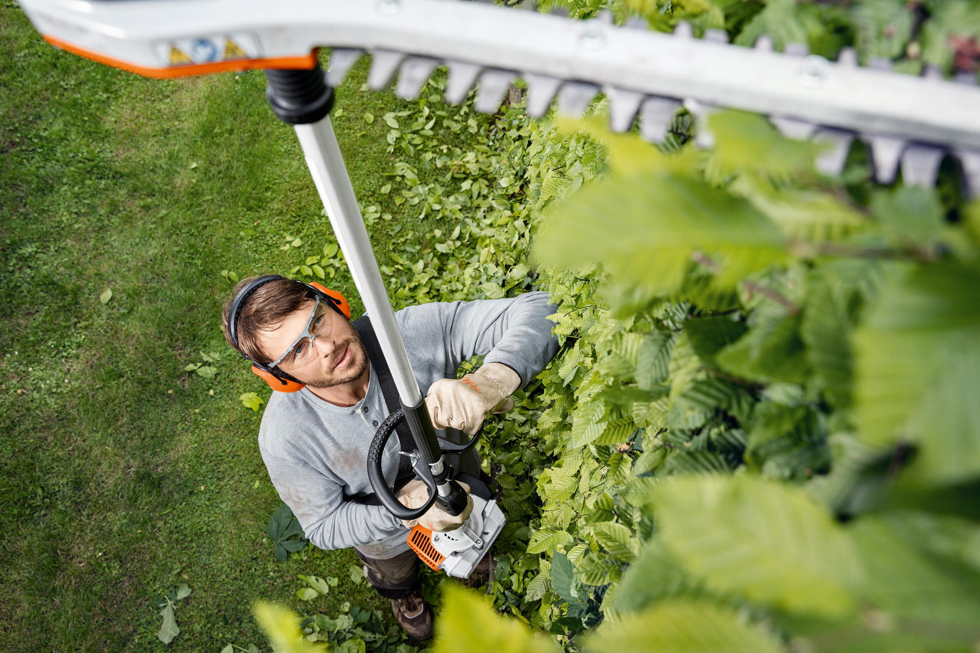 Uomo con abbigliamento protettivo che effettua un taglio sopratesta con il tagliasiepi STIHL HL 94